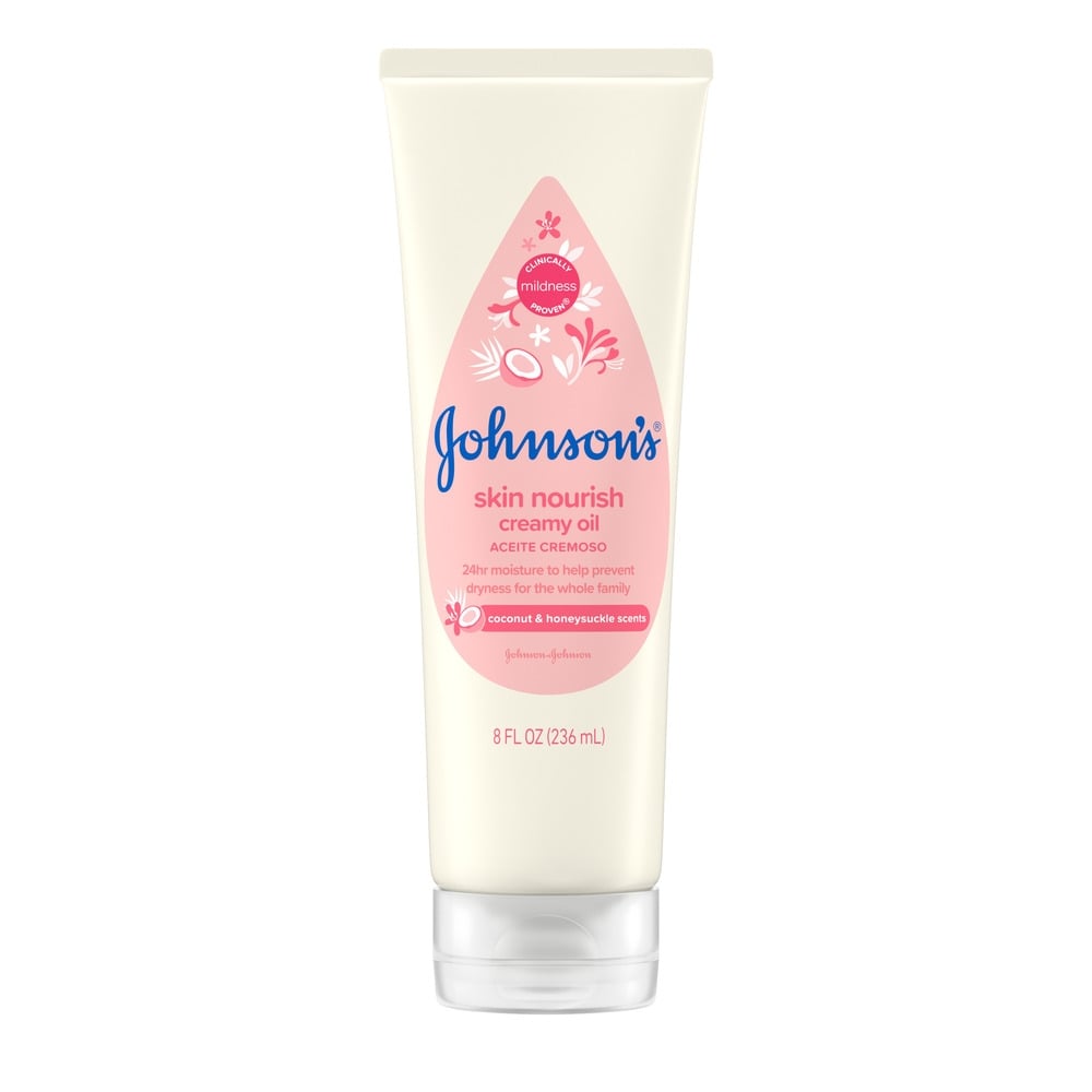 Envase de aceite cremoso: Johnson's Skin Nourish Creamy Oil en un pomo de 8 fl oz (236 ml) con una etiqueta rosa. El texto incluye: "Aromas de coco y madreselva", "24 horas de humectación", "Suavidad probada clínicamente" y "Johnson & Johnson".