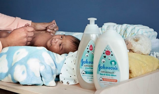 Bebé junto a productos para el cuidado de la piel del recién nacido de Johnson's®